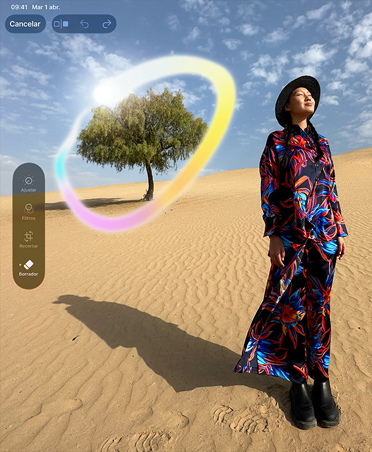 Imagen de una mujer con un vestido de colores de pie en un desierto con un árbol de fondo, rodeado por un círculo de colores que muestra la capacidad de Apple Intelligence para borrar objetos del fondo
