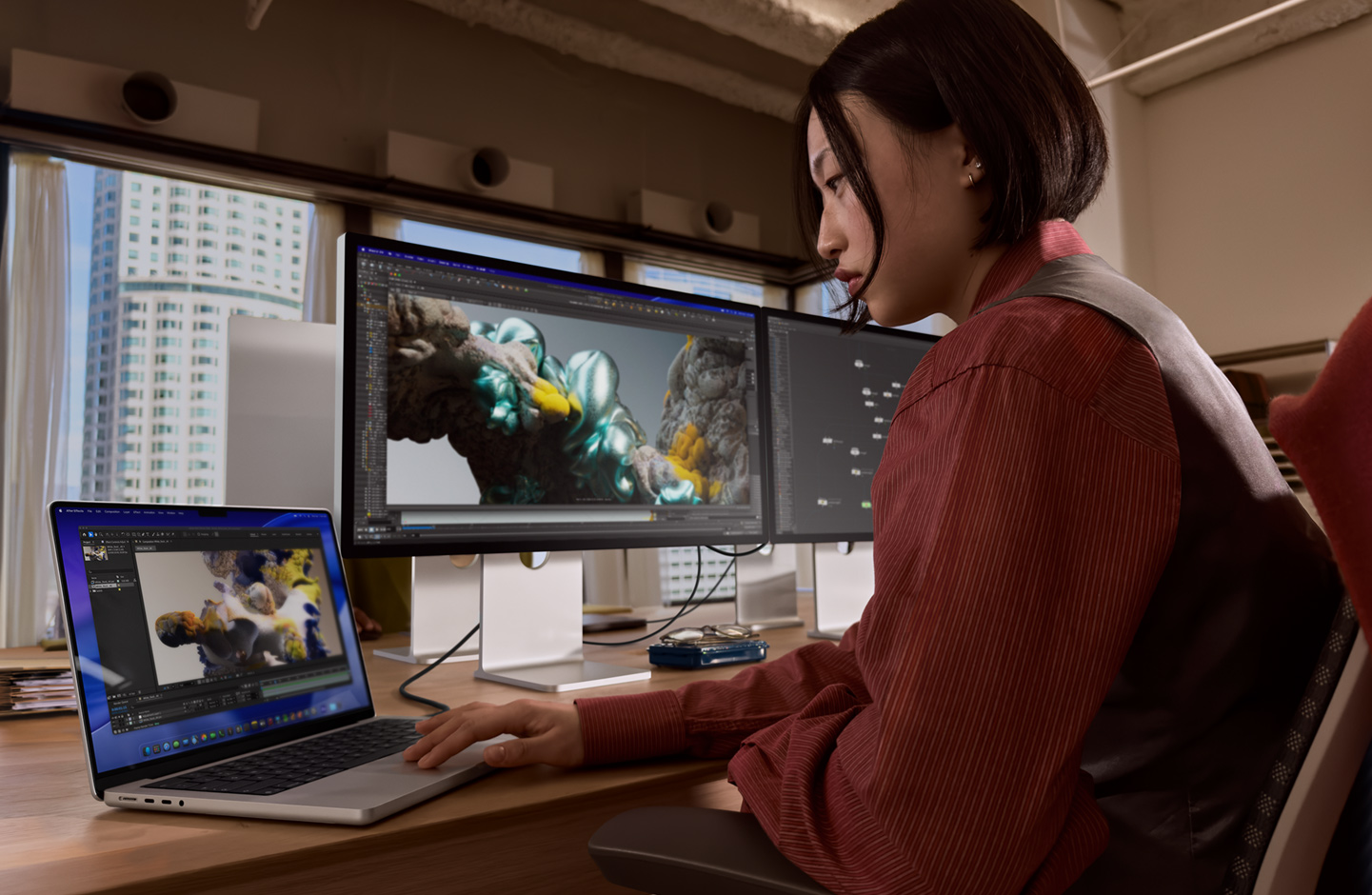 Inimene töötab kontoris MacBooki sülearvutiga, mis on ühendatud Thunderbolt 5 liidese kaudu Studio Display XDR-iga