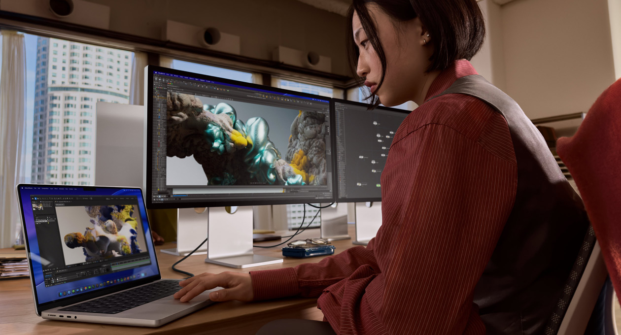 Iemand die op kantoor werkt op een MacBook-laptop die via een Thunderbolt 5-poort is verbonden met een Studio Display XDR