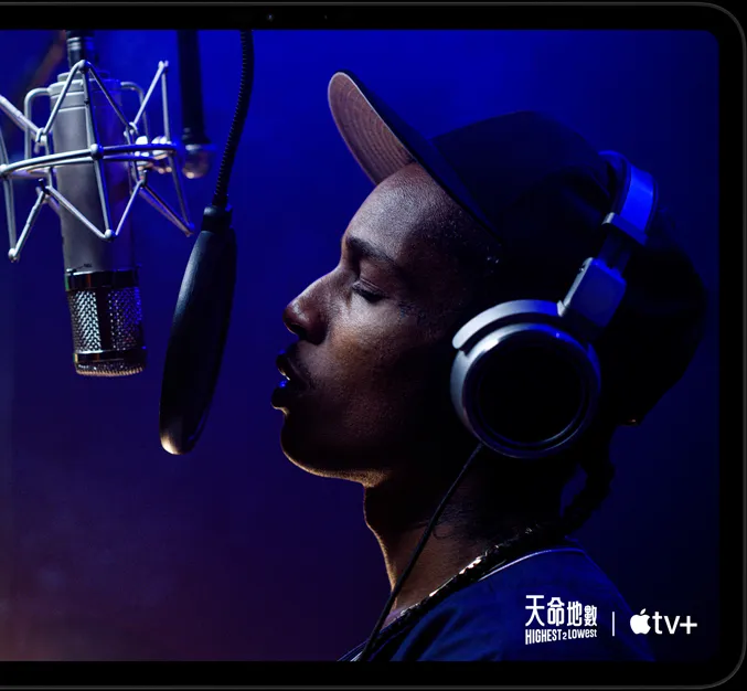 iPad Pro, landscape orientation, front exterior, space black color, rounded corners, black display bezel, display showing AppleTV+ playing a scene from  the Apple TV+ original film Highest 2 Lowest with ASAP Rocky as Yung Felon rapping into a microphone