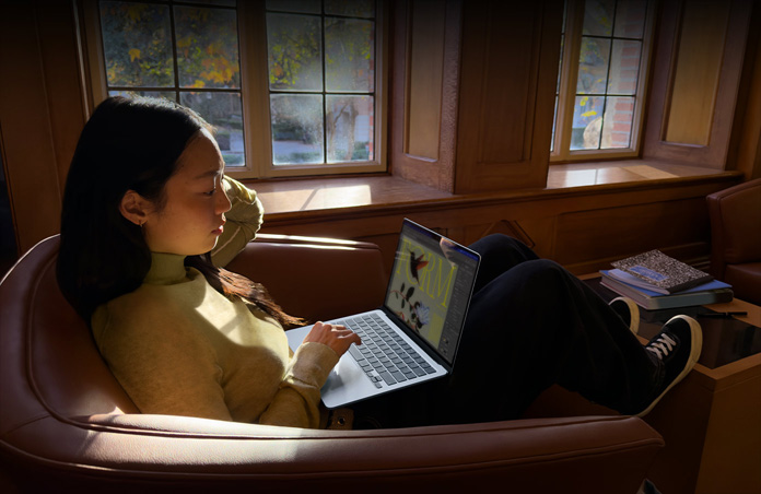 Egy fotelben ülő ember MacBook Airt használ