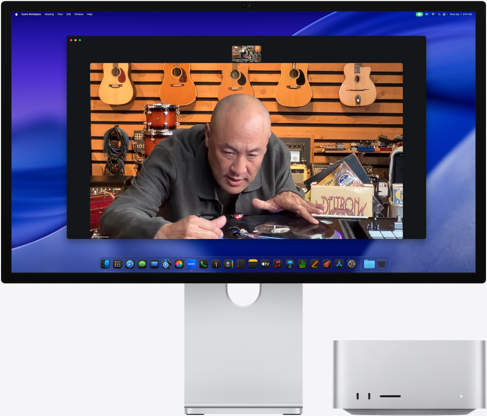 Asmuo, kalbantis vaizdo skambučiu per „Studio Display XDR“, po kuriuo padėtas „Mac Studio“, muzikos parduotuvėje, žiūri į patefoną