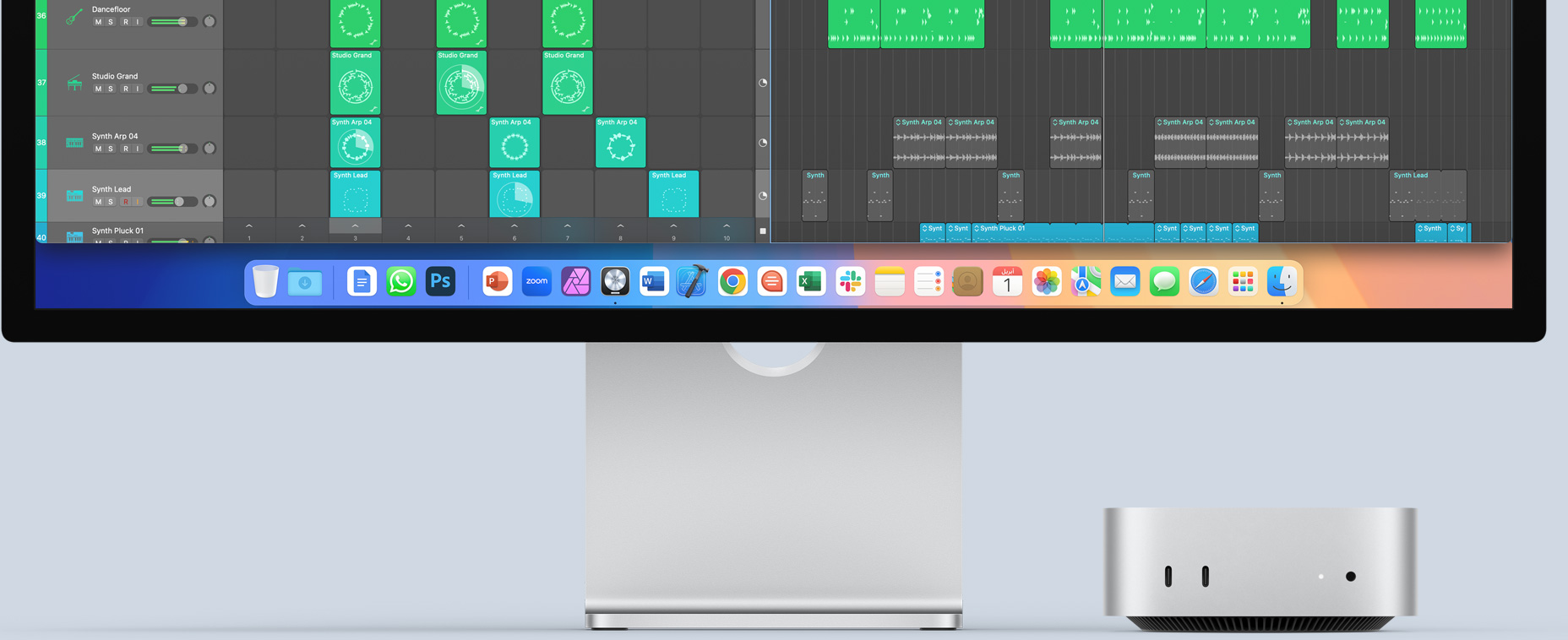 الجهة الأمامية من جهاز Mac&nbsp;mini فضي اللون تعرض المنافذ الأمامية وضوء مؤشر التشغيل، في وضعية مناسبة أسفل شاشة Mac تعرض شاشة مفعمة بالألوان إلى جانب أيقونات التطبيقات في شريط الأيقونات
