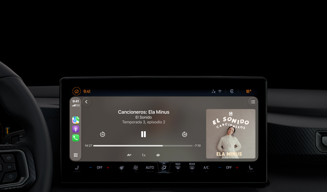Interior de un auto, la pantalla de la consola central muestra Apple Podcasts reproduciéndose a través de CarPlay con el podcast "Cancioneros: Ela Minus" de El Sonido, aparecen los controles de reproducción para retroceder, pausar y avanzar.