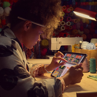 Una persona sentada en un escritorio usa dos dedos en la pantalla de un iPad para ampliar una imagen.