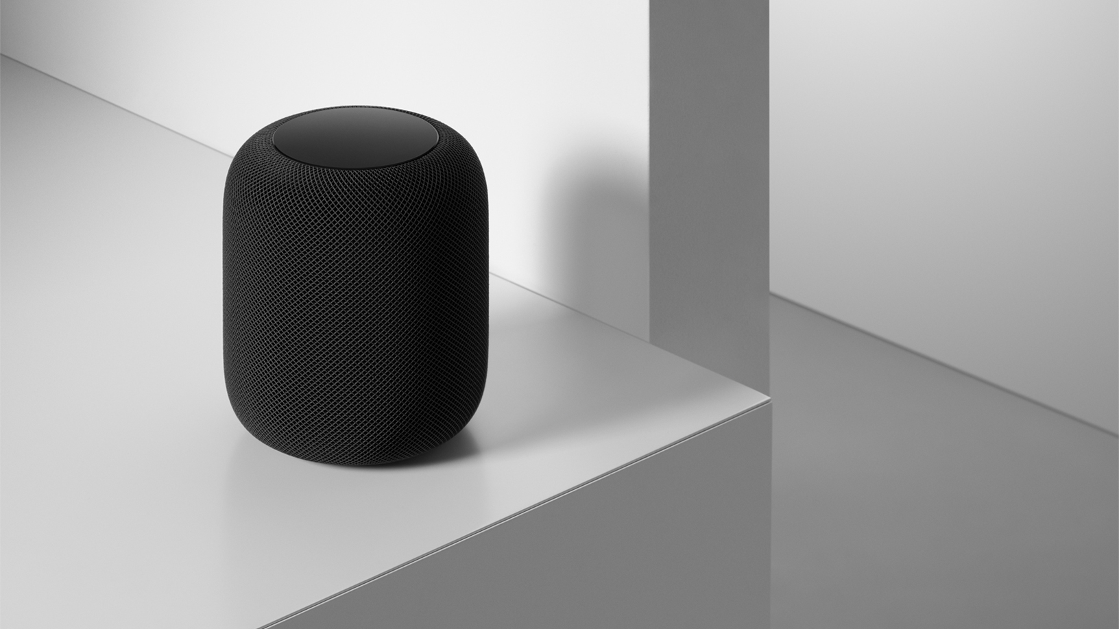 A space grey HomePod on a table.