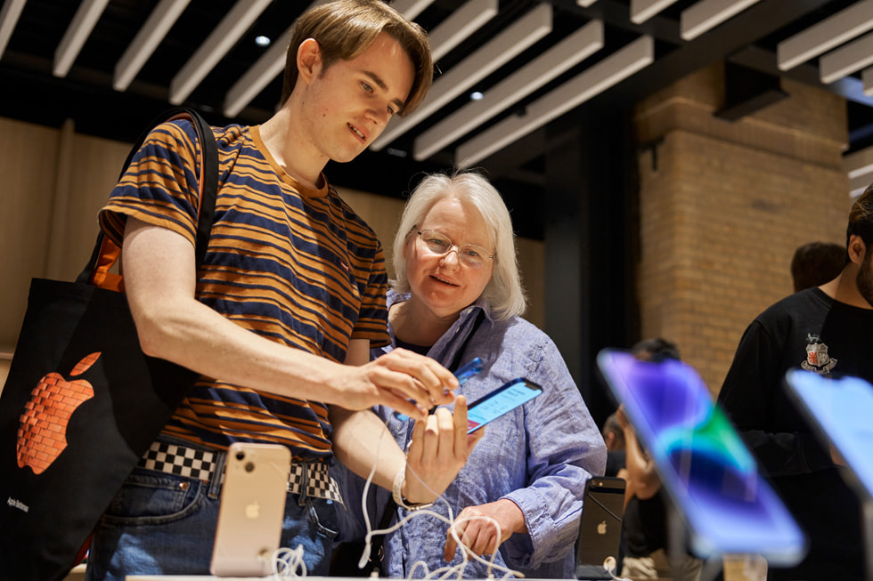 Two customers explore the iPhone 14 lineup at Apple Battersea.