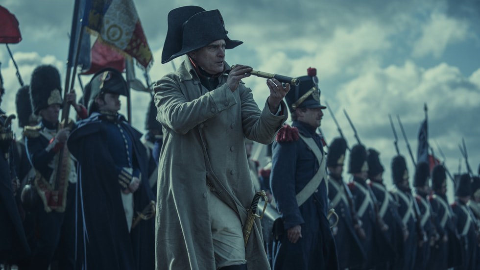 A still from “Napoleon” shows star Joaquin Phoenix as Napoleon on a battlefield.