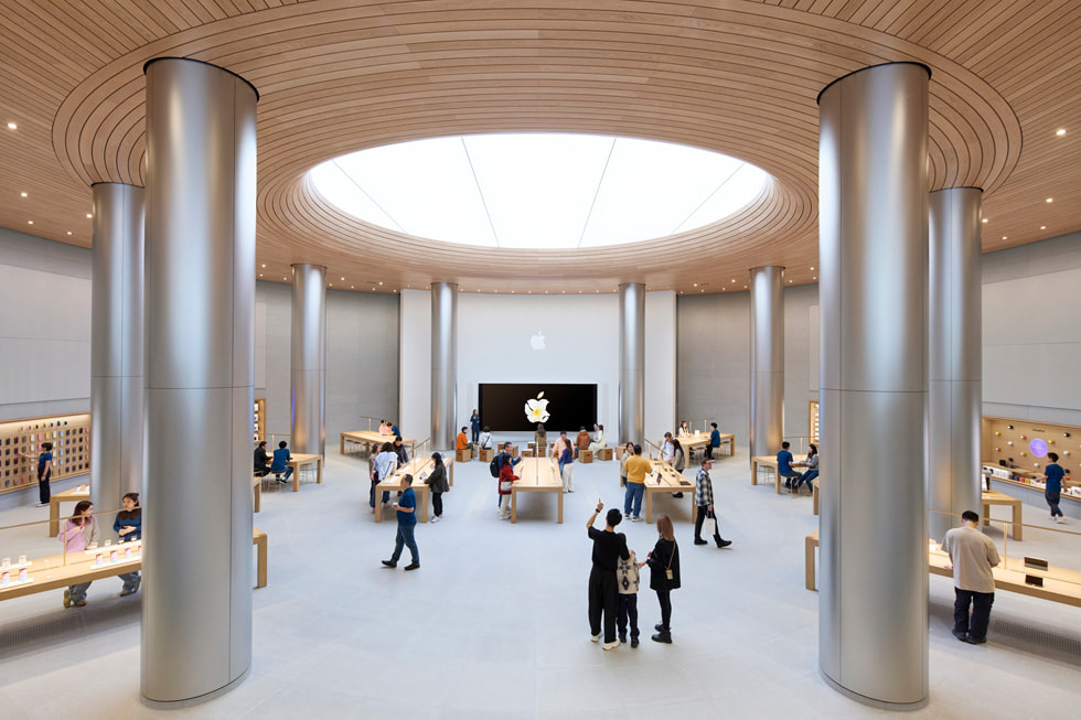 Customers look at Apple products and walk around the Forum inside the store. 
