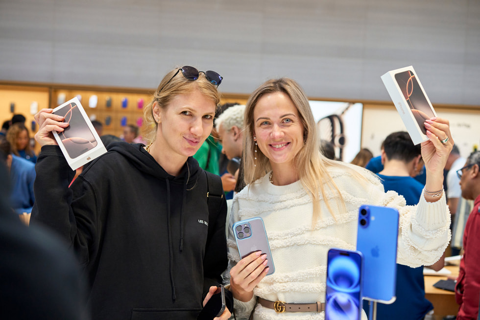 Deux clientes souriantes tiennent des boîtes d’iPhone 16 Pro à Apple Fifth Avenue, à New York.