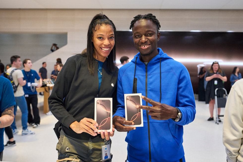 Une employée et un client souriants montrent des boîtes d’iPhone 16 Pro à Apple Fifth Avenue, à New York.