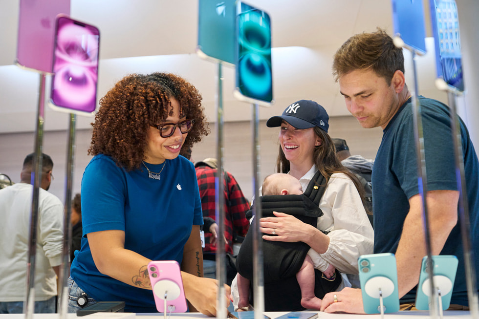 Une employée présente à un couple de clients la nouvelle gamme iPhone 16 à Apple Fifth Avenue, à New York.