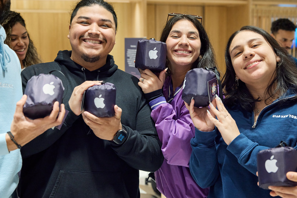 Customers show off commemorative Apple Miami Worldcenter picnic blankets at Apple Miami Worldcenter.