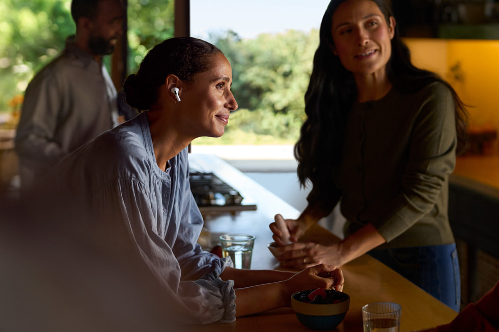 A user wearing AirPods Pro 2 sits at a counter in a cafe-like atmosphere.