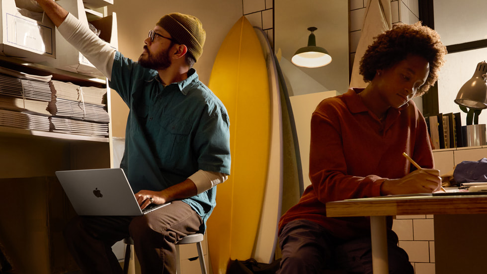 Bir Mac kullanıcısı yüksek bir raftaki malzemelere uzanırken bir elinde MacBook Air tutuyor.