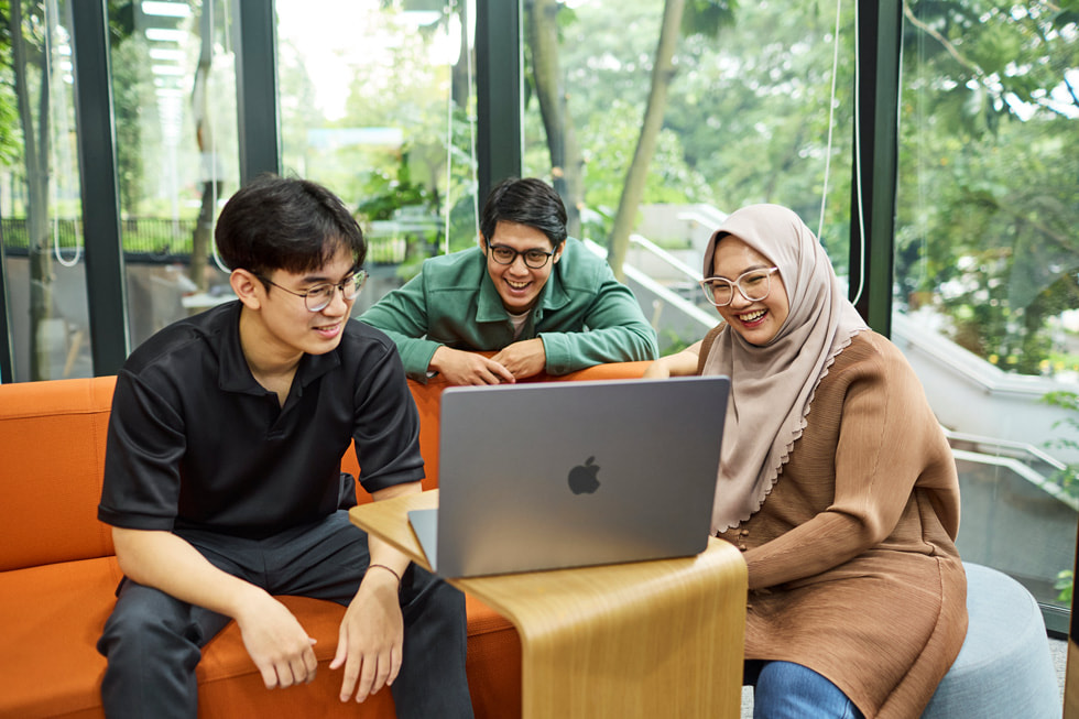 Tiga orang duduk mengelilingi komputer MacBook di Apple Developer Academy di Indonesia 