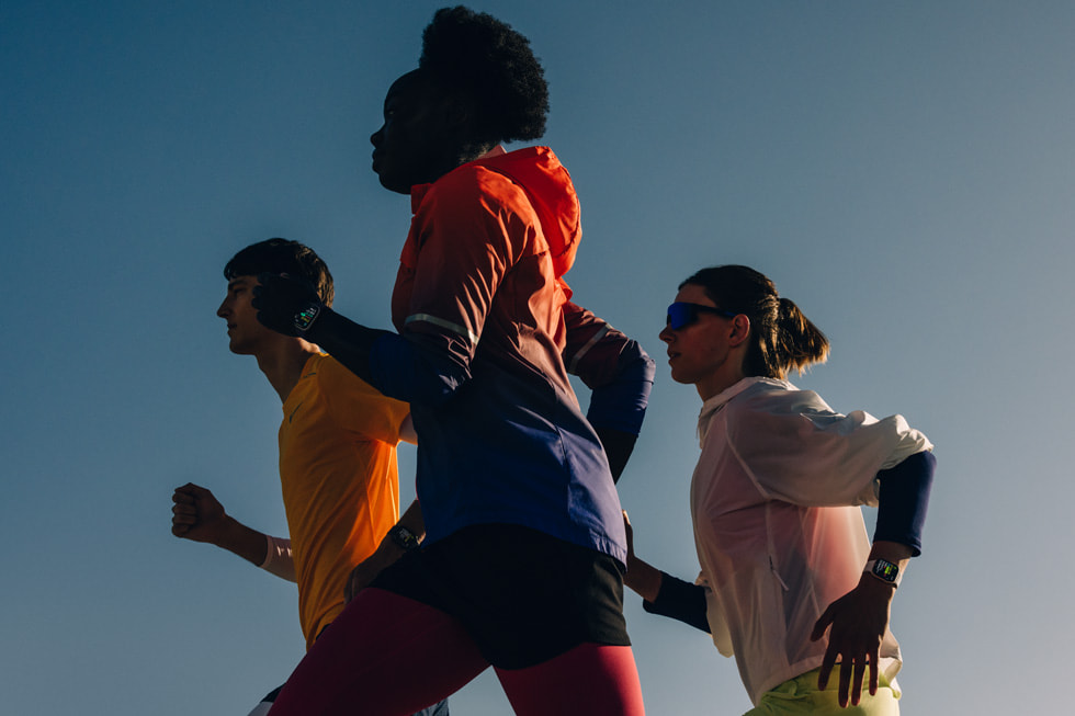 Tre personer med Apple Watch Series 11 på sig som springer utomhus.