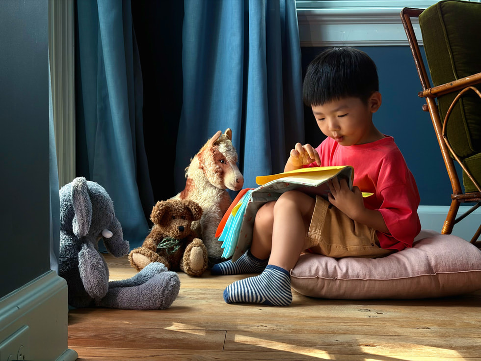 A photo taken with iPhone 17 features a child reading a book.