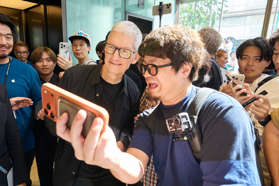 A customer is shown taking a selfie with Tim Cook in Apple Ginza.