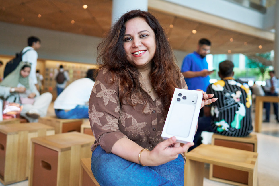 A smiling customer holds up their new iPhone 17 Pro purchase at Apple BKC in Mumbai.