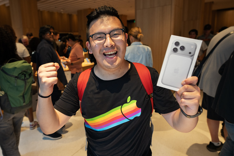 A customer in an Apple t-shirt smiles and holds their iPhone 17 Pro in silver at Apple Downtown Detroit.