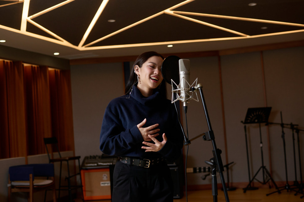 MONICA bernyanyi dengan mikrofon di studio musik.