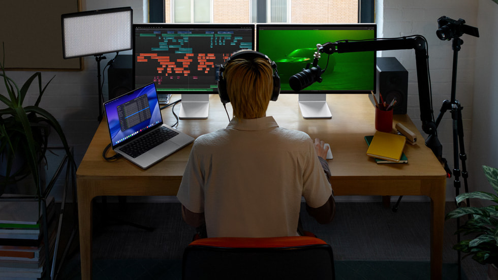 A person sitting at their workstation working on a project in Final Cut Pro on multiple screens.