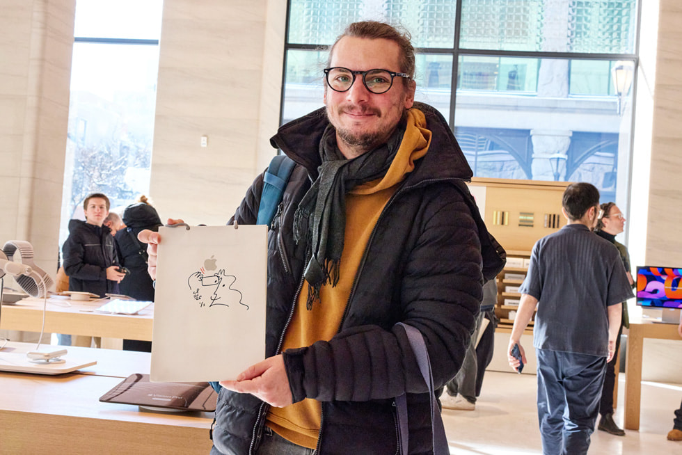 A customer holds up a bag featuring one of Catherine Potvin’s hand-drawn illustrations at Apple Sainte-Catherine.