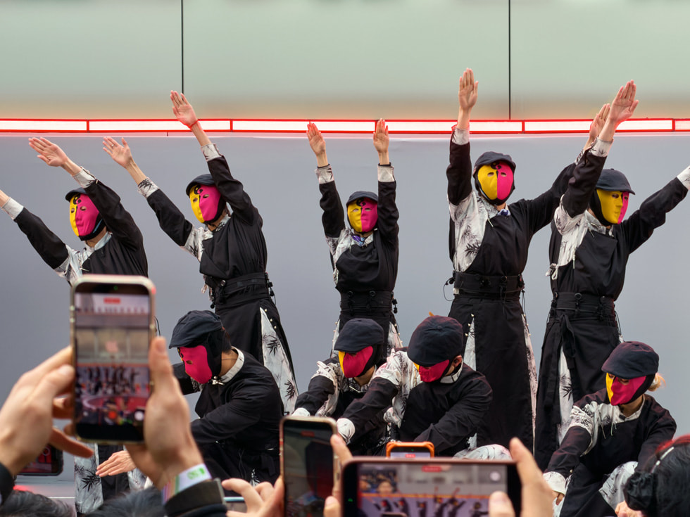 중국 Apple 타이쿠 리 청두에서 주황색과 붉은색 마스크를 쓴 댄서들이 공연하는 모습.