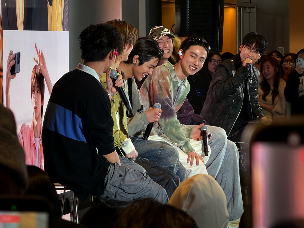 서울 Apple 명동에서 마이크를 손에 들고 미소 짓고 앉아 있는 밴드 CORTIS 멤버들의 모습.