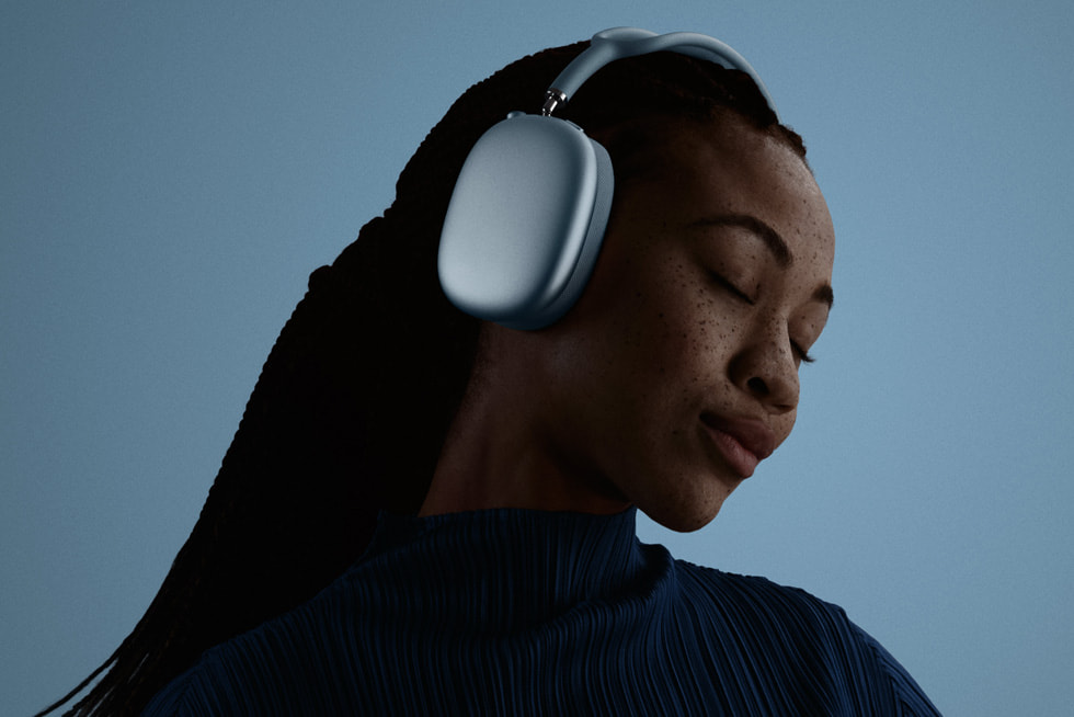 A user is pictured with their eyes closed wearing AirPods Max 2 in blue.