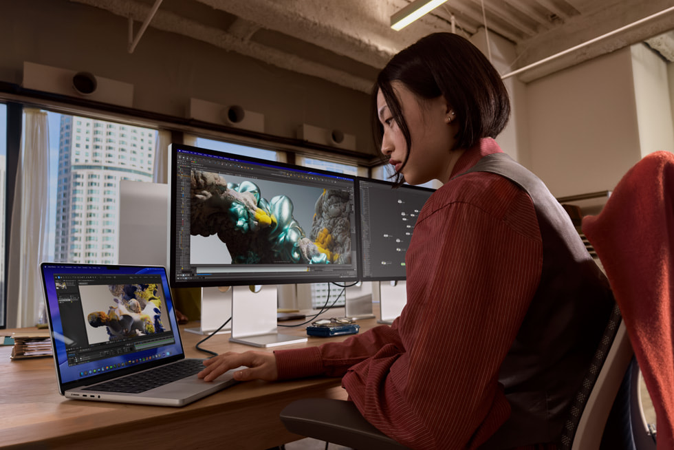 A MacBook Pro user works at their desk with two external displays.