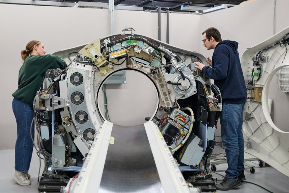 Two people are shown working on an MRI machine at the Block Imaging facility. 