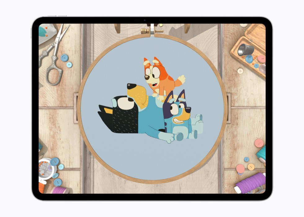 Un’istantanea del gioco stitch. che mostra un punto croce completato raffigurante due personaggi di “Bluey” all’interno di un telaio di legno.