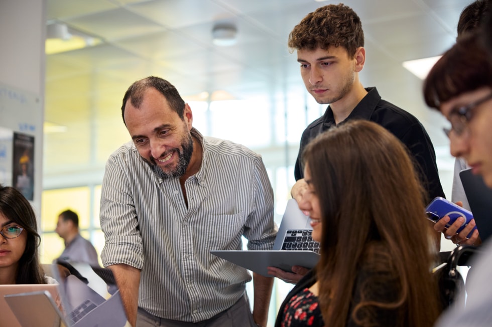 Docente della Apple Developer Academy di Napoli che osserva il progetto di uno studente in aula, mentre il resto della classe guarda.