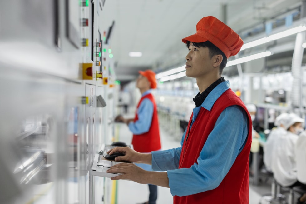 Hình ảnh hai công nhân đang vận hành máy móc tại nhà máy.