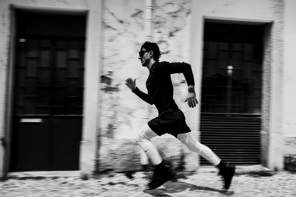 A black-and-white photo of a runner wearing Apple Watch Ultra 4 sprints outdoors. 