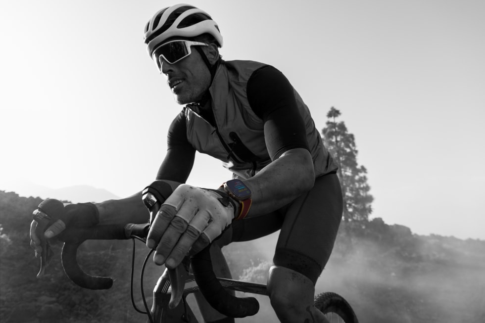 A black-and-white photo of a bicyclist wearing Apple Watch Ultra 4.