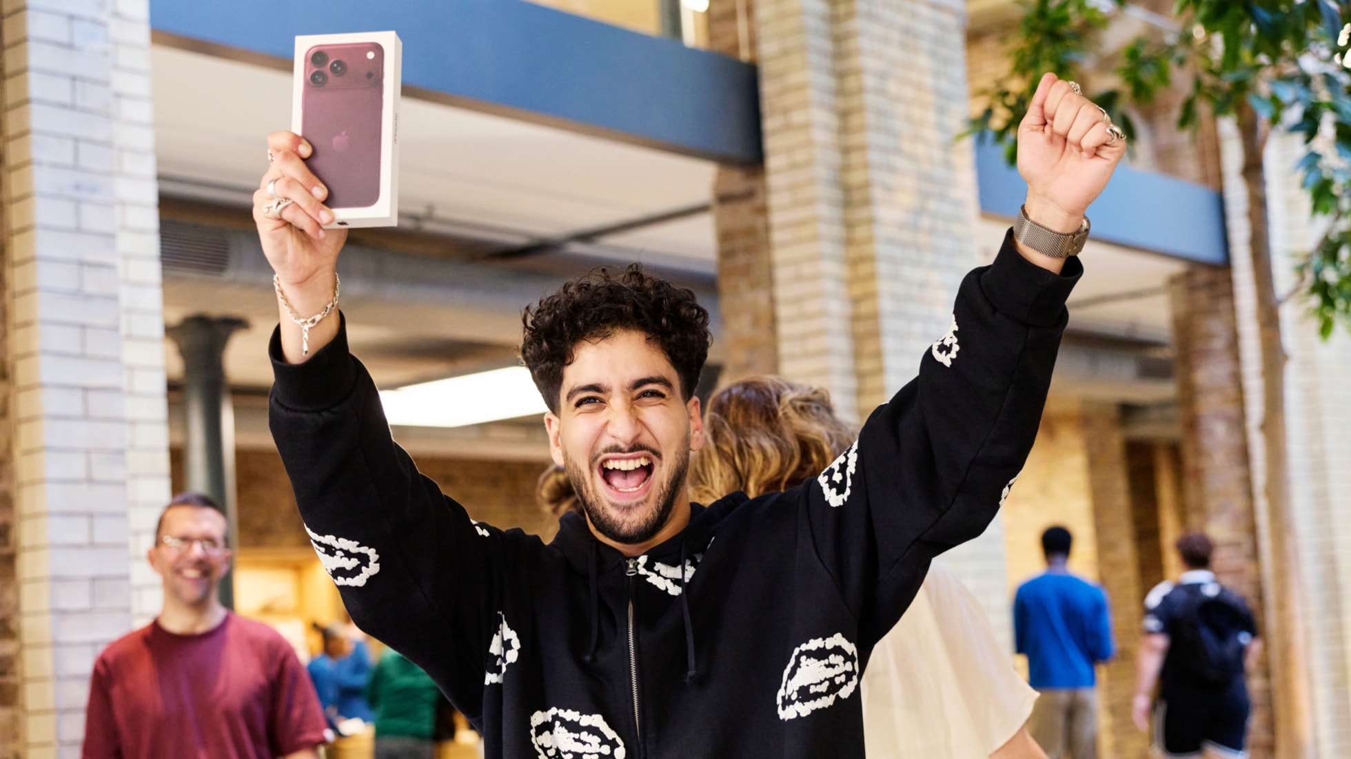A customer celebrates the purchase of a burgundy iPhone 18 Pro.