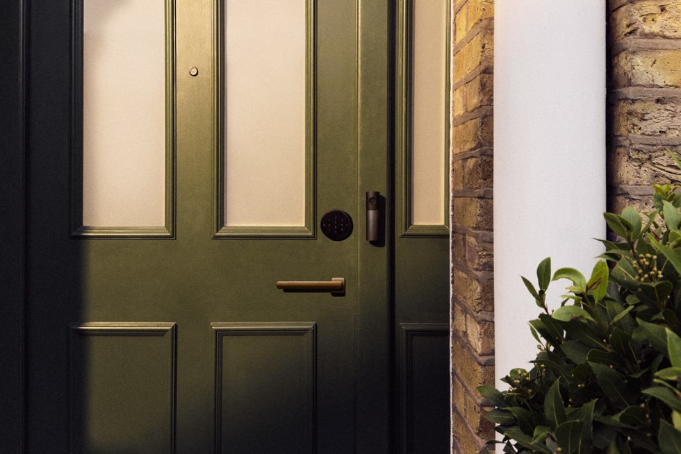 Smart Deadbolt Lock and Video Doorbell are featured on a dark green front door.
