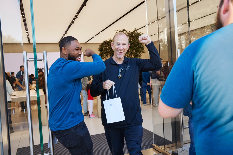 A smiling customer holds a bag with their new purchase at Apple Domain NORTHSIDE as a team member cheers.