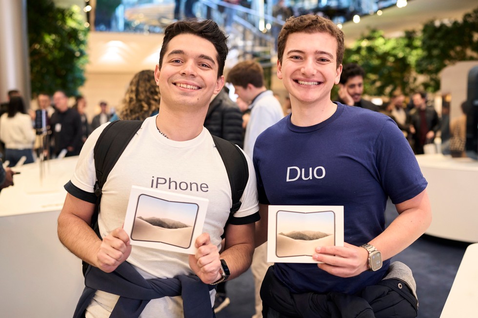 Two customers hold up their iPhone Duo boxes at Apple Fifth Avenue.