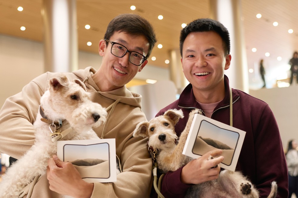 Two customers hold their iPhone Duo purchases along with their dogs at Apple Jing’an.