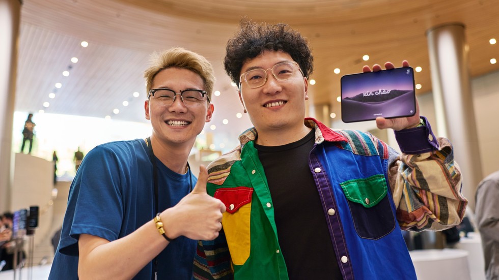 At Apple Jing’an, a customer holds iPhone Duo next to an Apple team member who is giving a thumbs-up.
