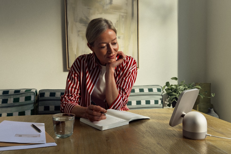 A person sits at their kitchen table and reads a book next to HomeView.