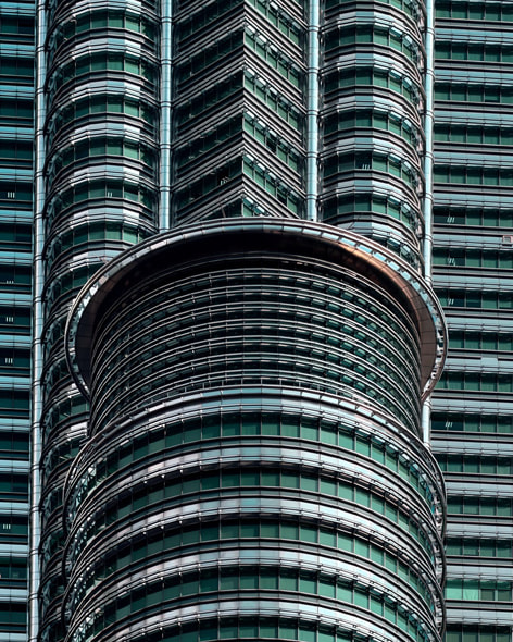 Gros plan en angle d’une partie de tours jumelles de Kuala Lumpur se découpant sur un fond de ciel bleu nuageux.