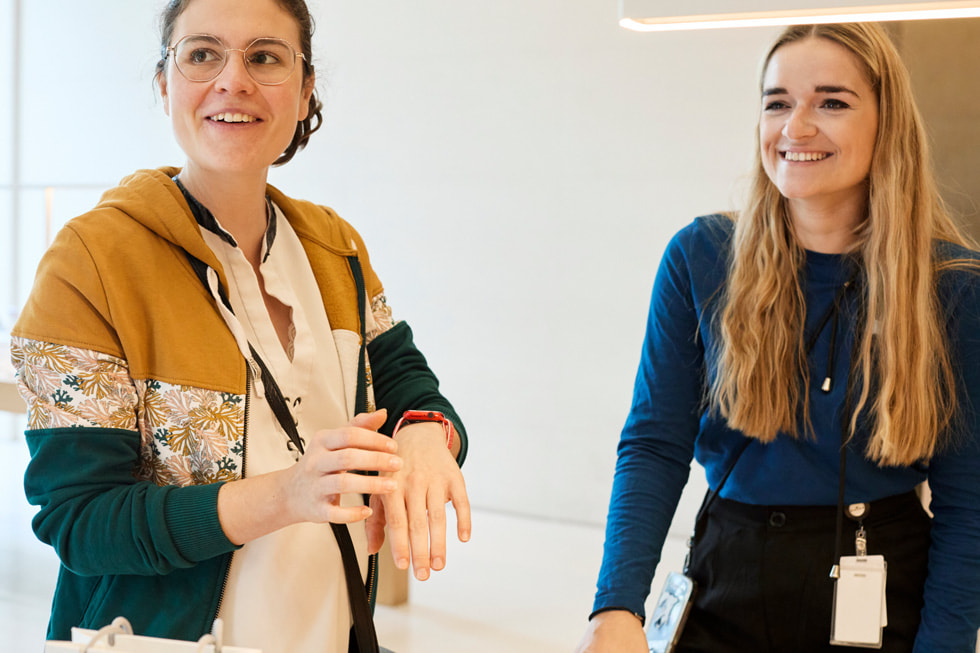 A customer wearing an Apple Watch compares their device to an Apple Watch display model at Apple Champs-Élysées.