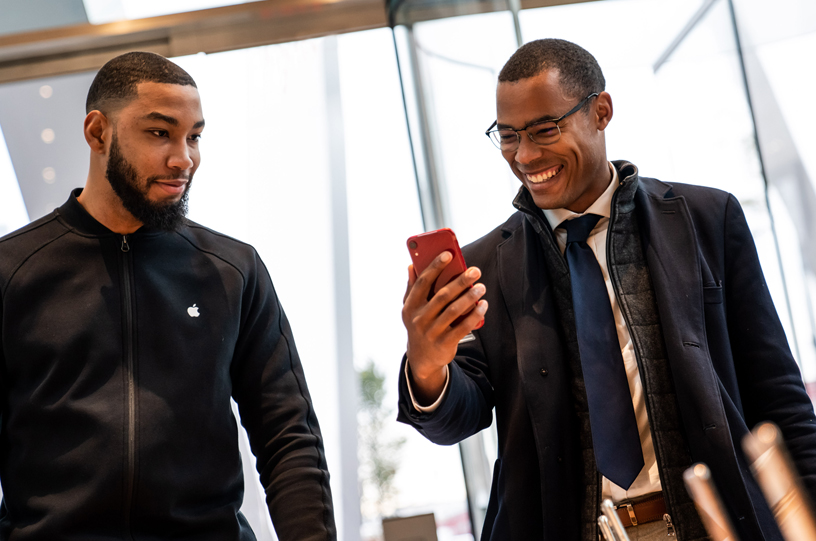 An Apple Downtown Brooklyn team member assisting a customer with the iPhone XR PRODUCT(RED).