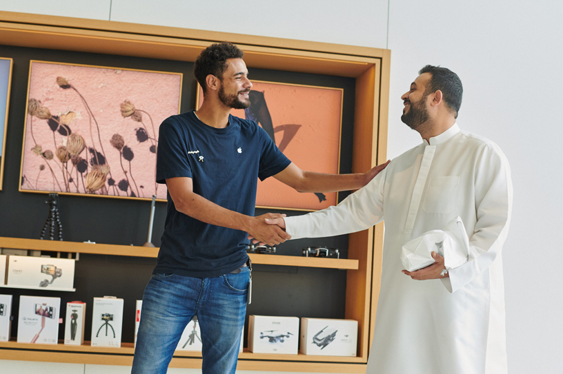 An Apple team member shaking hands with a customer.