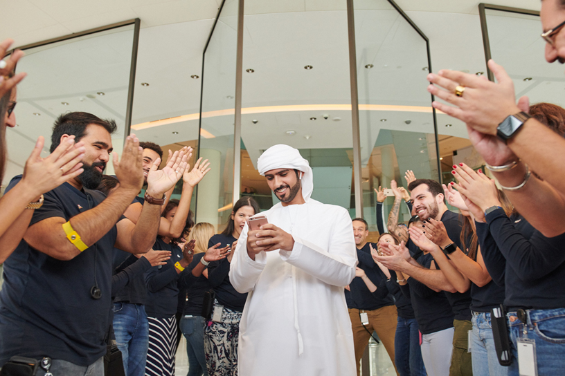 Customer surrounded by clapping Apple team members.